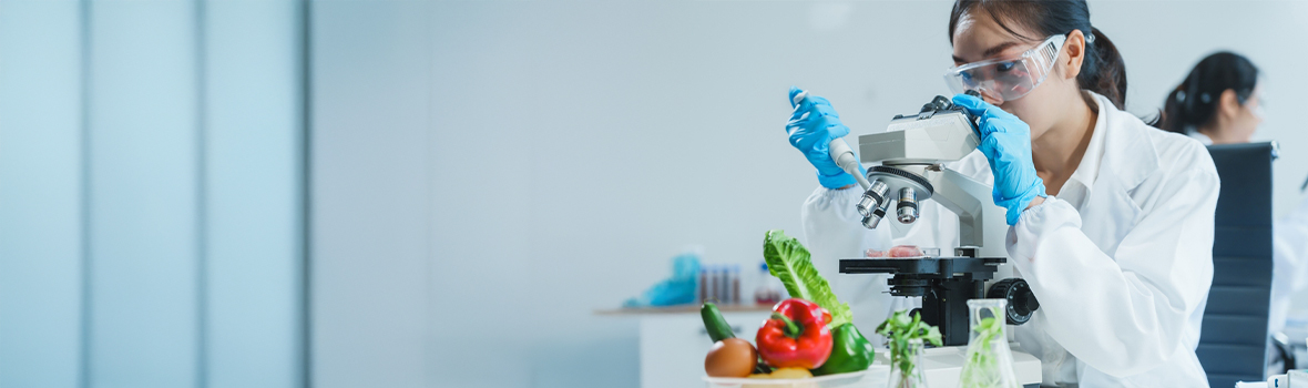 Asian woman working in a lab on food research, using a microscope